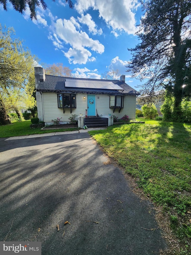 view of front of home with a front lawn and solar panels