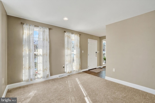 foyer entrance featuring plenty of natural light and dark carpet