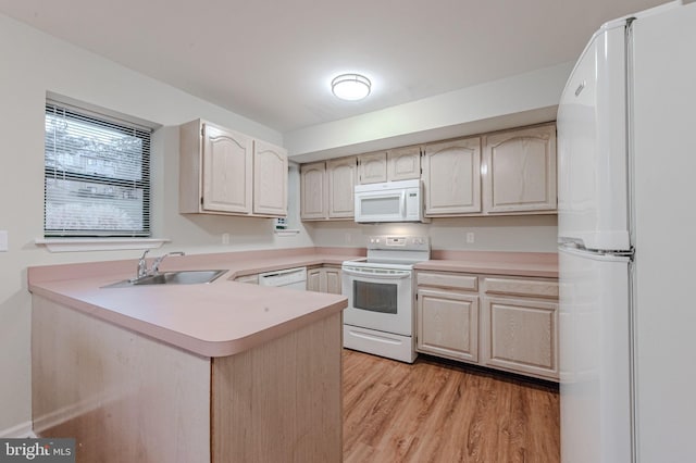 kitchen with sink, white appliances, light hardwood / wood-style flooring, and kitchen peninsula