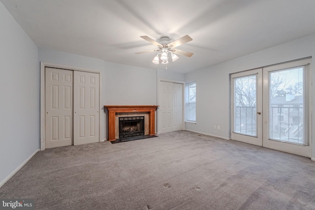 unfurnished living room featuring light colored carpet, a tile fireplace, ceiling fan, and french doors