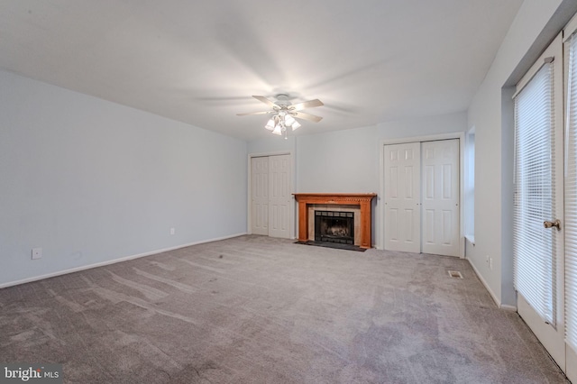 unfurnished living room with ceiling fan, carpet, and a fireplace