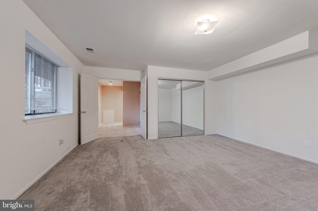 unfurnished bedroom featuring light carpet and a closet