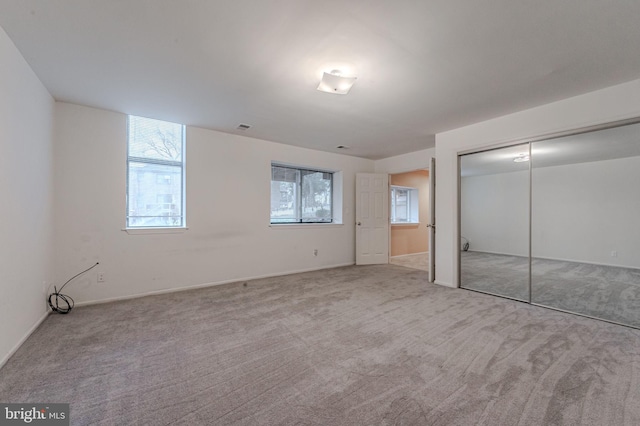 unfurnished bedroom featuring light carpet and a closet