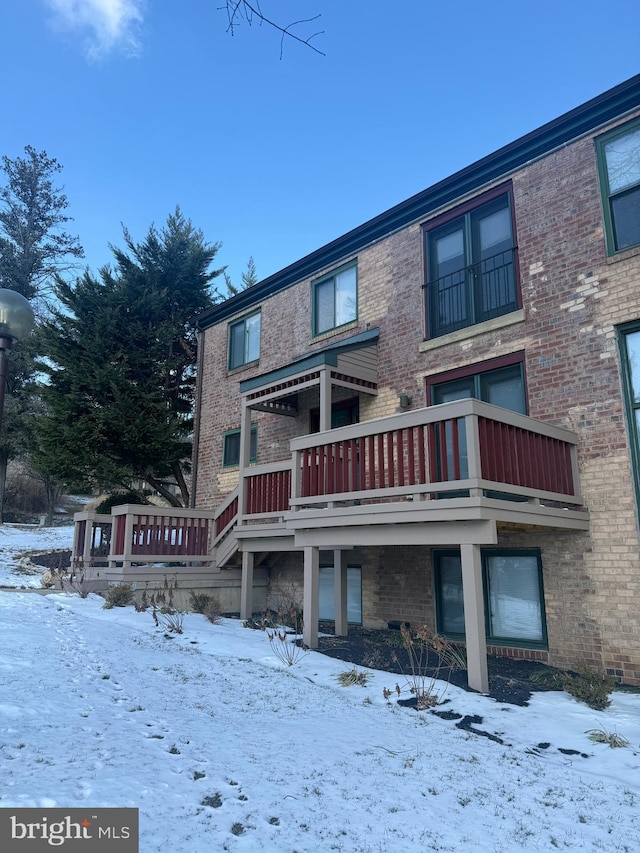 snow covered rear of property featuring a balcony