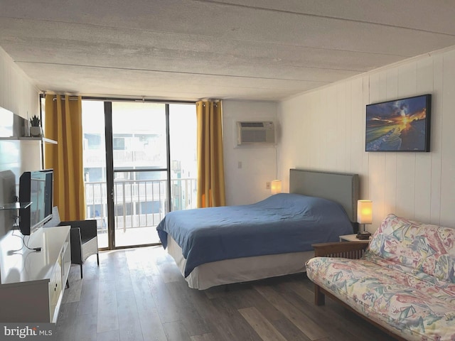 bedroom with a wall of windows, a wall unit AC, wood-type flooring, and access to outside