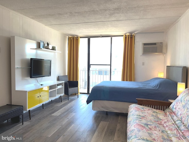 bedroom featuring access to exterior, wooden walls, a wall mounted AC, expansive windows, and dark hardwood / wood-style flooring