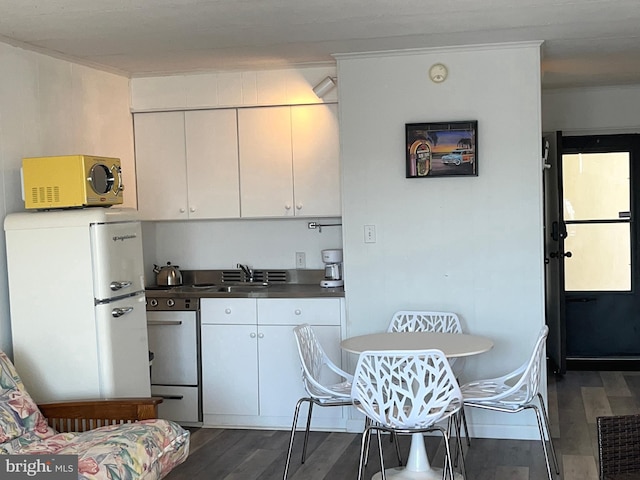 kitchen featuring dark hardwood / wood-style flooring, sink, white fridge, and white cabinets