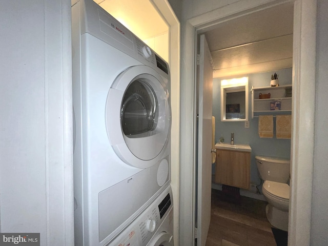 washroom with dark wood-type flooring and stacked washer and dryer