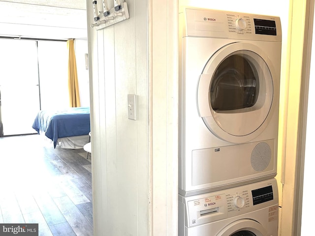 laundry room with stacked washer / dryer and wood-type flooring