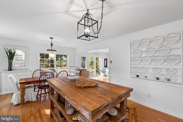 dining space with crown molding, a chandelier, and light wood-type flooring