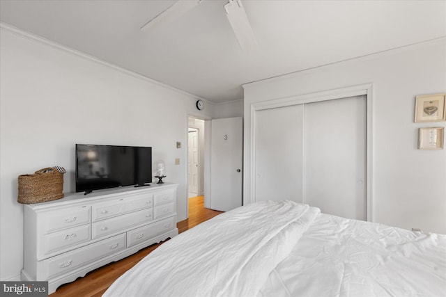 bedroom with light hardwood / wood-style flooring, ornamental molding, a closet, and ceiling fan