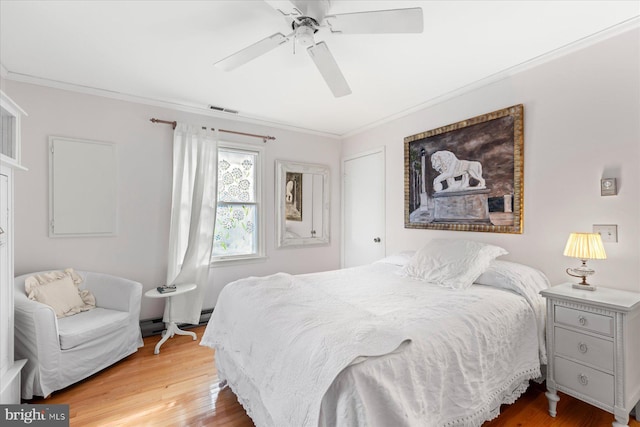 bedroom with hardwood / wood-style flooring, crown molding, ceiling fan, and baseboard heating