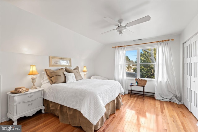 bedroom featuring lofted ceiling, a closet, ceiling fan, and light wood-type flooring