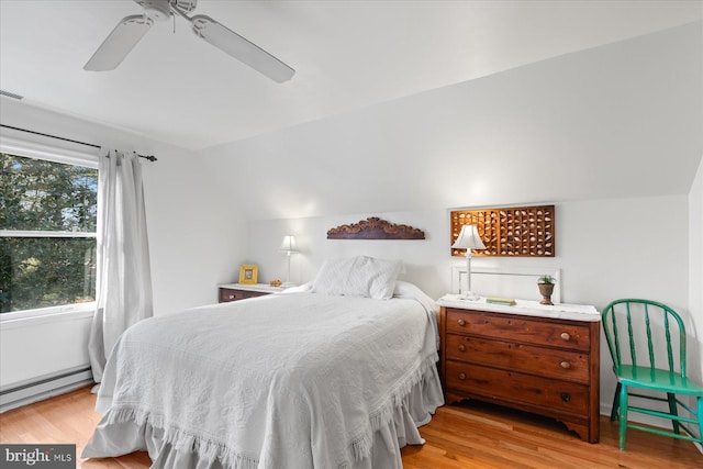 bedroom featuring ceiling fan, vaulted ceiling, light hardwood / wood-style flooring, and a baseboard heating unit