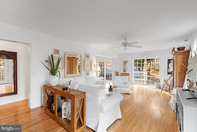 living room featuring crown molding, light hardwood / wood-style floors, and ceiling fan