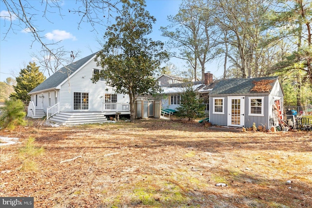 rear view of house featuring a wooden deck and an outdoor structure