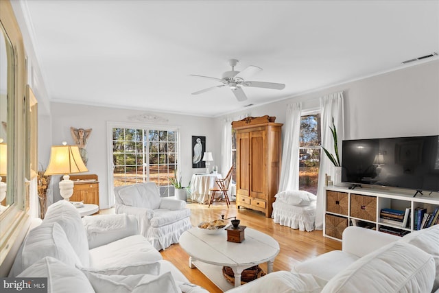 living room featuring crown molding, ceiling fan, and light hardwood / wood-style flooring