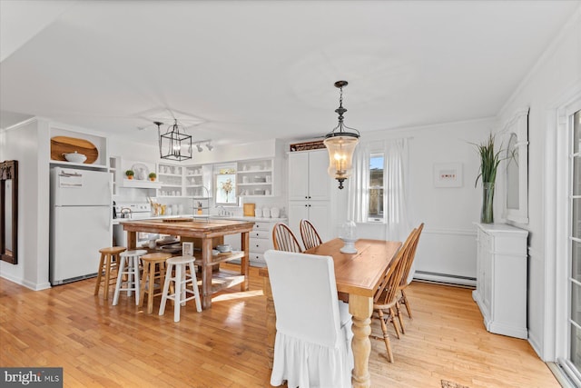 dining room featuring sink, a baseboard heating unit, a notable chandelier, light wood-type flooring, and built in shelves