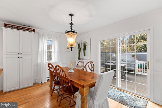 dining space featuring ornamental molding, a baseboard heating unit, and light hardwood / wood-style floors