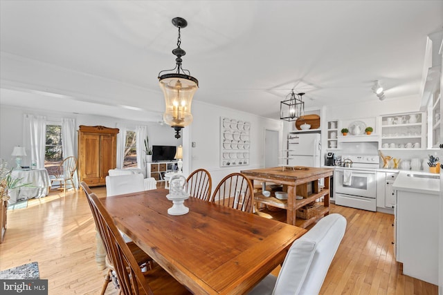 dining area featuring an inviting chandelier, sink, and light hardwood / wood-style floors