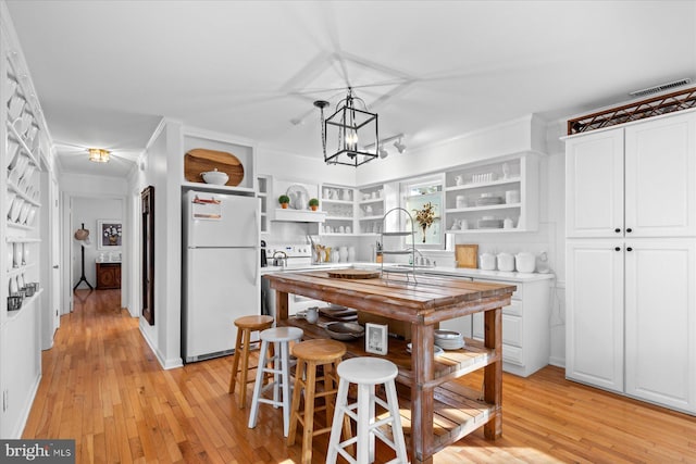 kitchen with decorative light fixtures, light wood-type flooring, built in features, white appliances, and white cabinets