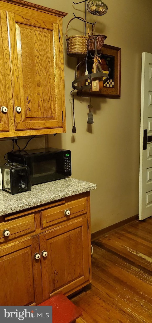 kitchen with dark wood-type flooring and light stone counters