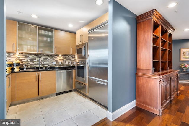 kitchen with built in appliances, sink, and tasteful backsplash