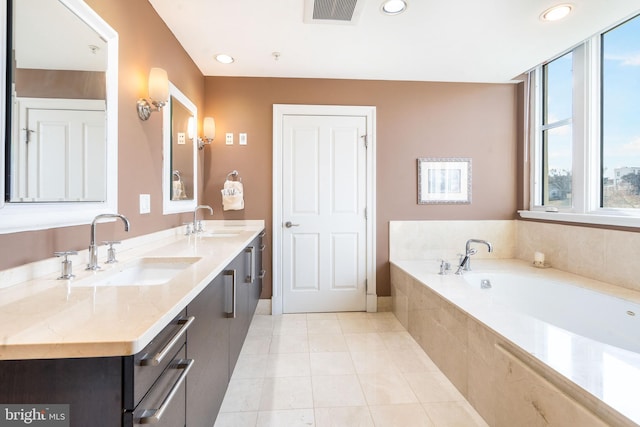 bathroom featuring tile patterned floors, vanity, and tiled bath