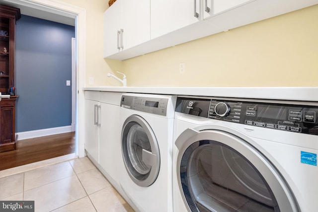 laundry room with light tile patterned flooring, cabinets, and washer and dryer