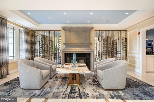 living room with a raised ceiling, ornamental molding, and a large fireplace