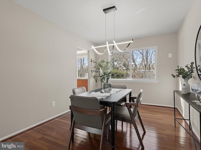 dining space featuring dark wood-type flooring and an inviting chandelier