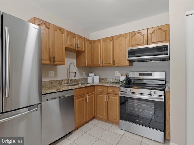 kitchen featuring light stone counters, sink, light tile patterned flooring, and appliances with stainless steel finishes