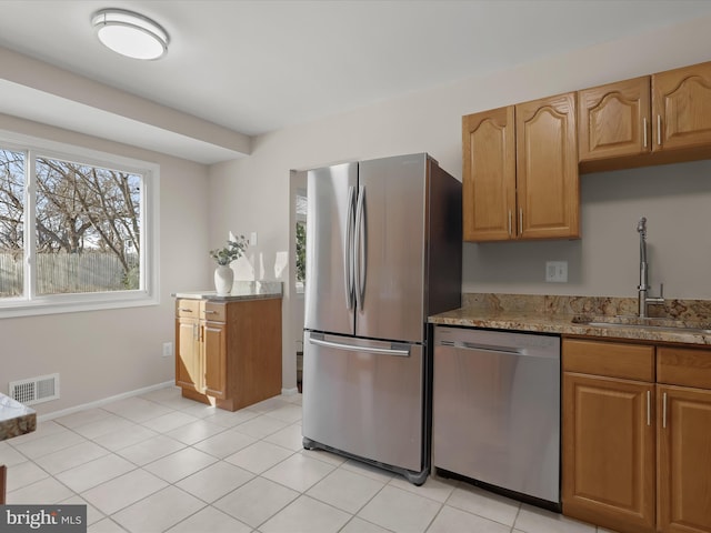 kitchen featuring stainless steel appliances, light tile patterned flooring, sink, and light stone counters