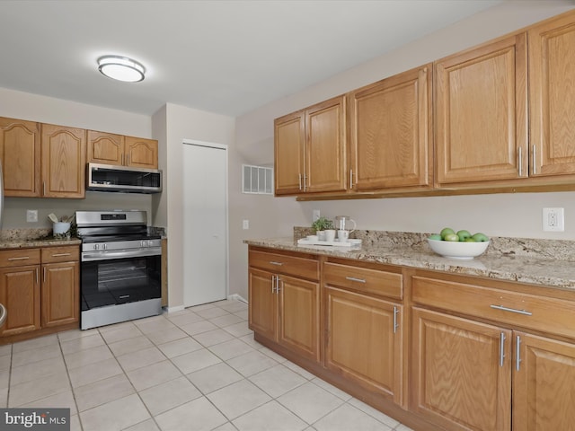 kitchen featuring light stone counters, appliances with stainless steel finishes, and light tile patterned floors