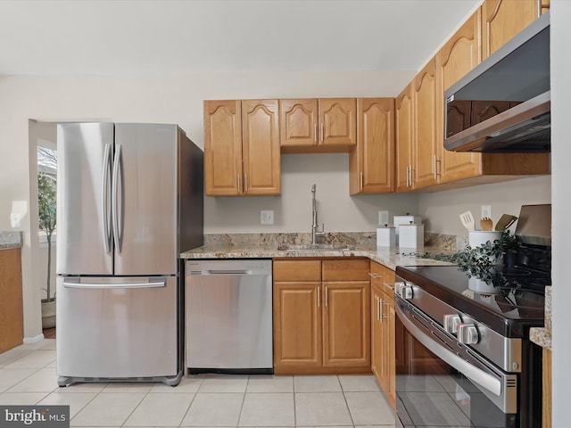 kitchen featuring appliances with stainless steel finishes, light stone countertops, sink, and light tile patterned floors