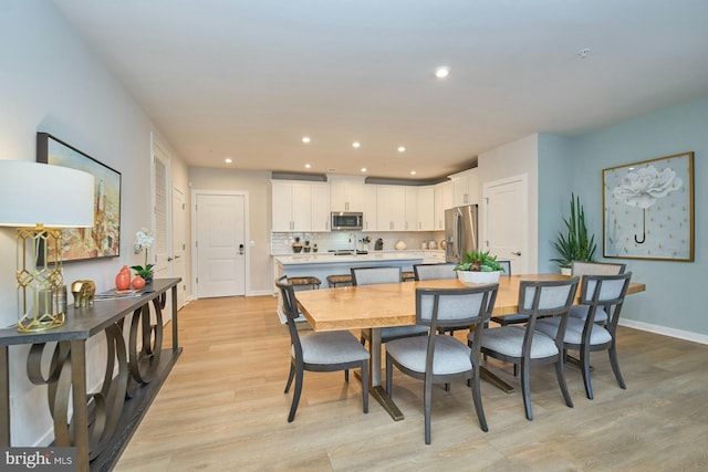 kitchen featuring appliances with stainless steel finishes, white cabinetry, backsplash, a center island, and light wood-type flooring