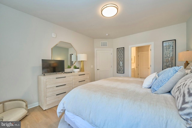 bedroom featuring connected bathroom and light hardwood / wood-style flooring