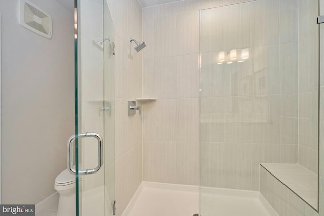 bathroom featuring toilet and a shower with shower door