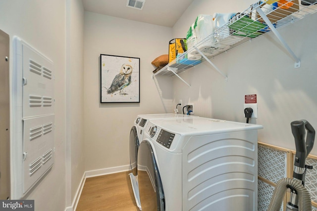 clothes washing area with separate washer and dryer and light wood-type flooring