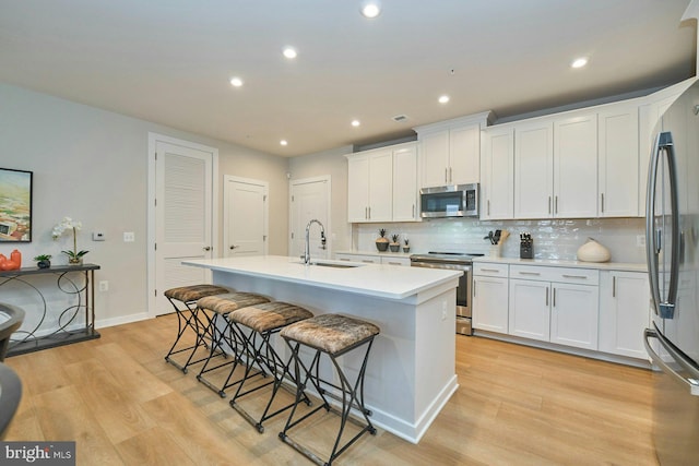 kitchen with white cabinetry, appliances with stainless steel finishes, a kitchen island with sink, and sink