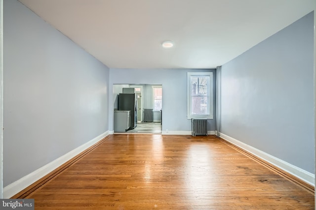 spare room featuring radiator heating unit and light hardwood / wood-style floors