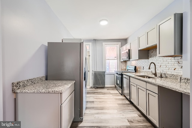 kitchen featuring stainless steel appliances, sink, light stone counters, and gray cabinets