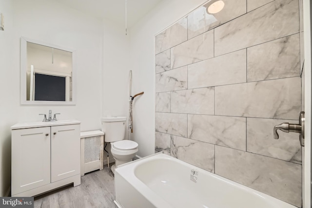 bathroom with a bathing tub, hardwood / wood-style floors, vanity, and toilet