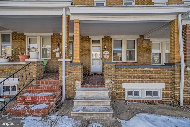 snow covered property entrance with covered porch