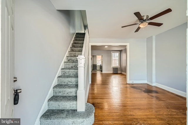 stairs featuring hardwood / wood-style flooring and ceiling fan