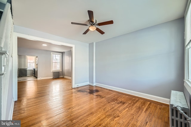 empty room with light hardwood / wood-style flooring, radiator heating unit, and ceiling fan