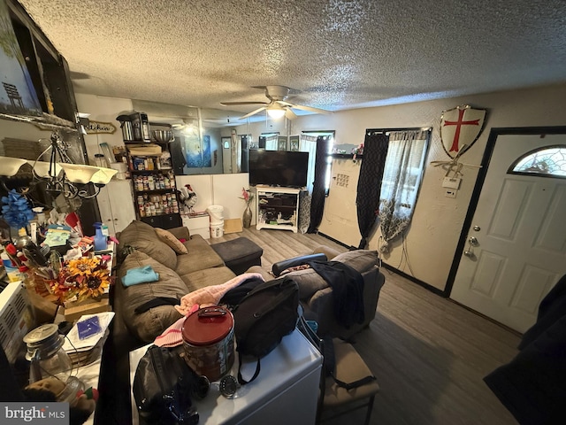 living room featuring ceiling fan, wood-type flooring, and a textured ceiling