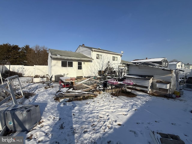 snow covered back of property with cooling unit and a jacuzzi