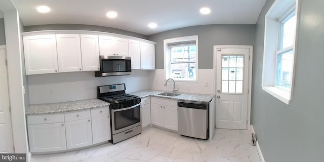 kitchen featuring tasteful backsplash, white cabinetry, appliances with stainless steel finishes, and sink