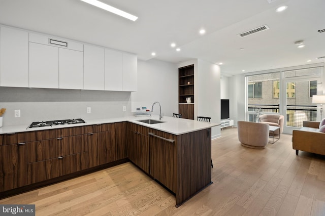 kitchen with white cabinetry, sink, kitchen peninsula, and stainless steel gas stovetop